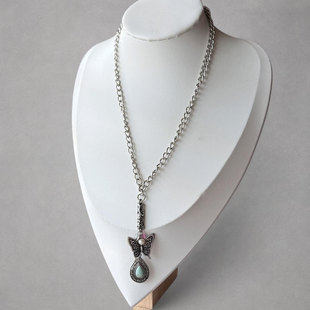 Silver-tone butterfly pendant necklace featuring an ornate butterfly charm .